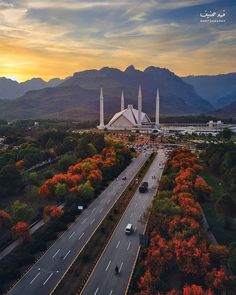 an aerial view of a city with mountains in the background and cars driving on the road