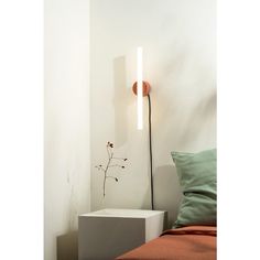 a lamp that is on the side of a wall next to a bed with pillows