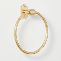 a gold towel ring on a white surface with a clip in the middle that is attached to it