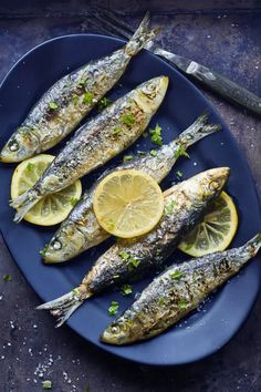 some fish are on a blue plate with lemon slices