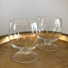 two empty wine glasses sitting on top of a metal tray with gold rimmings