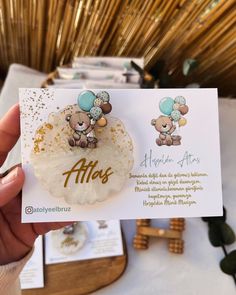 a person holding up a card with two teddy bears on it and gold foil lettering