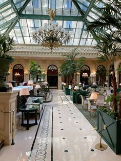 the inside of a hotel lobby with tables, chairs and chandeliers hanging from the ceiling