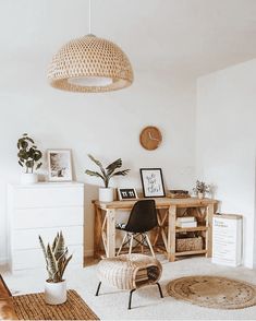 a living room with some plants and pictures on the wall next to a chair in front of a table