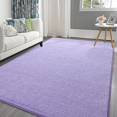 a purple rug in a living room next to a white couch and table with flowers on it