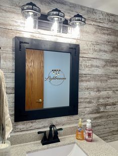 a bathroom sink with a mirror above it and lights on the wall next to it