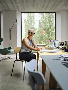 an older woman sitting at a desk in front of a window