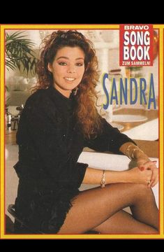 a woman sitting on top of a white couch next to a book with the title song book sandraa