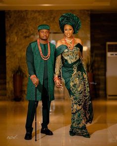 a man and woman dressed in traditional african garb standing next to each other holding hands