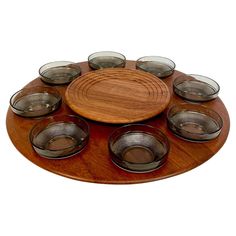 a wooden platter with nine glass bowls on it and a plate in the middle