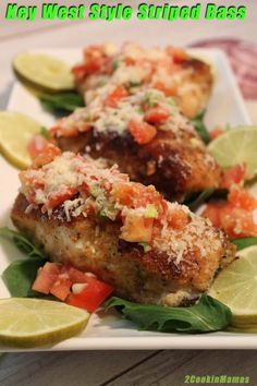 two pieces of meat on a plate with garnishes and limes