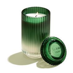 a green glass candle with a label next to it