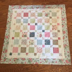 a quilted table topper sitting on the floor in front of a wooden floor