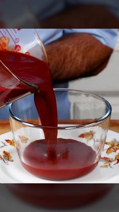 a person pouring red liquid into a glass bowl