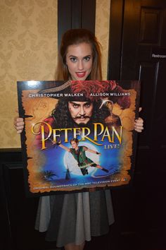 a woman is holding up a poster for peter pan