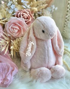 a pink stuffed rabbit sitting next to flowers