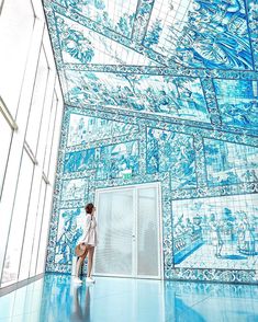 a woman is standing in front of a blue tiled room with glass walls and doors