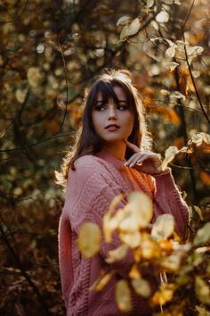 a woman is standing in the woods with her hand on her shoulder and looking off into the distance