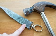 a person pointing at an old pair of scissors on a wooden table next to a hammer