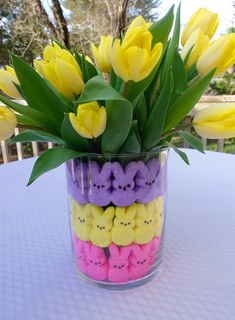 a vase filled with lots of yellow and purple peeppies sitting on top of a table