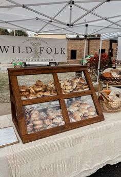 a table topped with lots of pastries under a white tent next to a sign