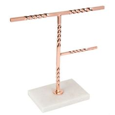 a small white marble stand with two metal bars on it's end and one pink gold plated base