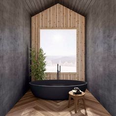 a black bath tub sitting inside of a bathroom next to a wooden floor and window