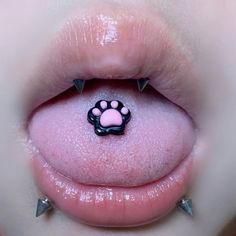 a close up of a person's tongue with spikes and a pink nose ring