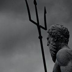 an old statue holding a large sception in front of a cloudy sky