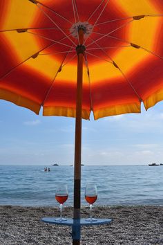 two glasses of wine under an umbrella on the beach