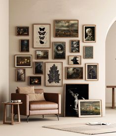 a living room filled with lots of framed pictures on the wall above a chair and table