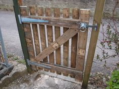 an open wooden gate on the side of a road