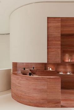 a circular bathroom with wooden shelves and sinks in the center, along with white walls