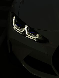 the front lights of a sports car are shown in this dark photo with only one light on