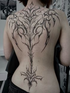 the back of a woman's body with an intricate tattoo design on her lower back