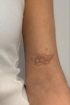 a woman's arm with a small tattoo on the wrist and an angel above it