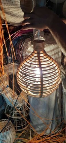 a person holding a lamp in their hand and some baskets on the ground next to it