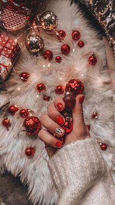 a woman's hand with red nail polish and christmas decorations