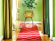 a green room with a red and white rug on the floor next to a chair