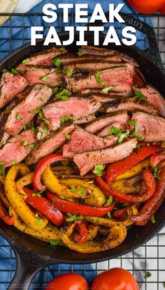 steak fajitas with peppers and tomatoes in a skillet on a blue surface