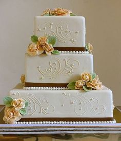 a three tiered wedding cake with gold flowers