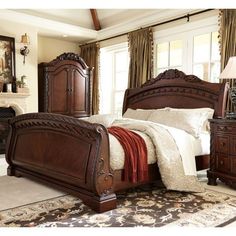 a bedroom with a bed, dresser and mirror in the corner next to a fireplace