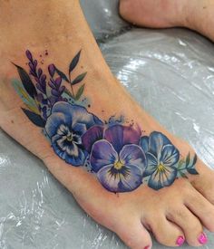 a foot tattoo with blue and purple flowers on it