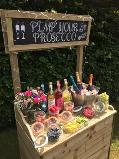 a wooden table topped with lots of bottles of wine and candy next to a chalkboard sign