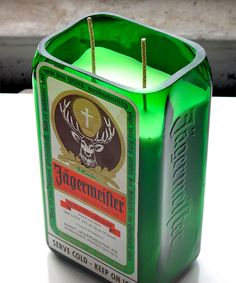 a green lit candle holder with an image of a deer head on the front and side