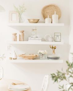 white shelves with plates, bowls and vases on them in a dining room setting