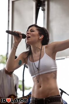 a woman singing into a microphone while holding her arm out to the side with one hand