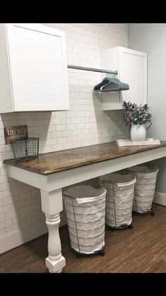 a laundry room with three trash cans under the counter