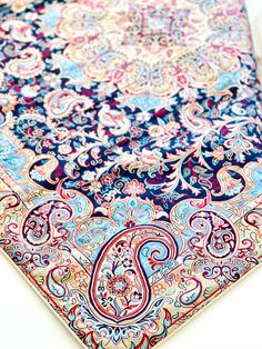 an intricately designed blue, red and pink area rug on a white tablecloth