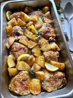 a pan filled with chicken and potatoes on top of a table